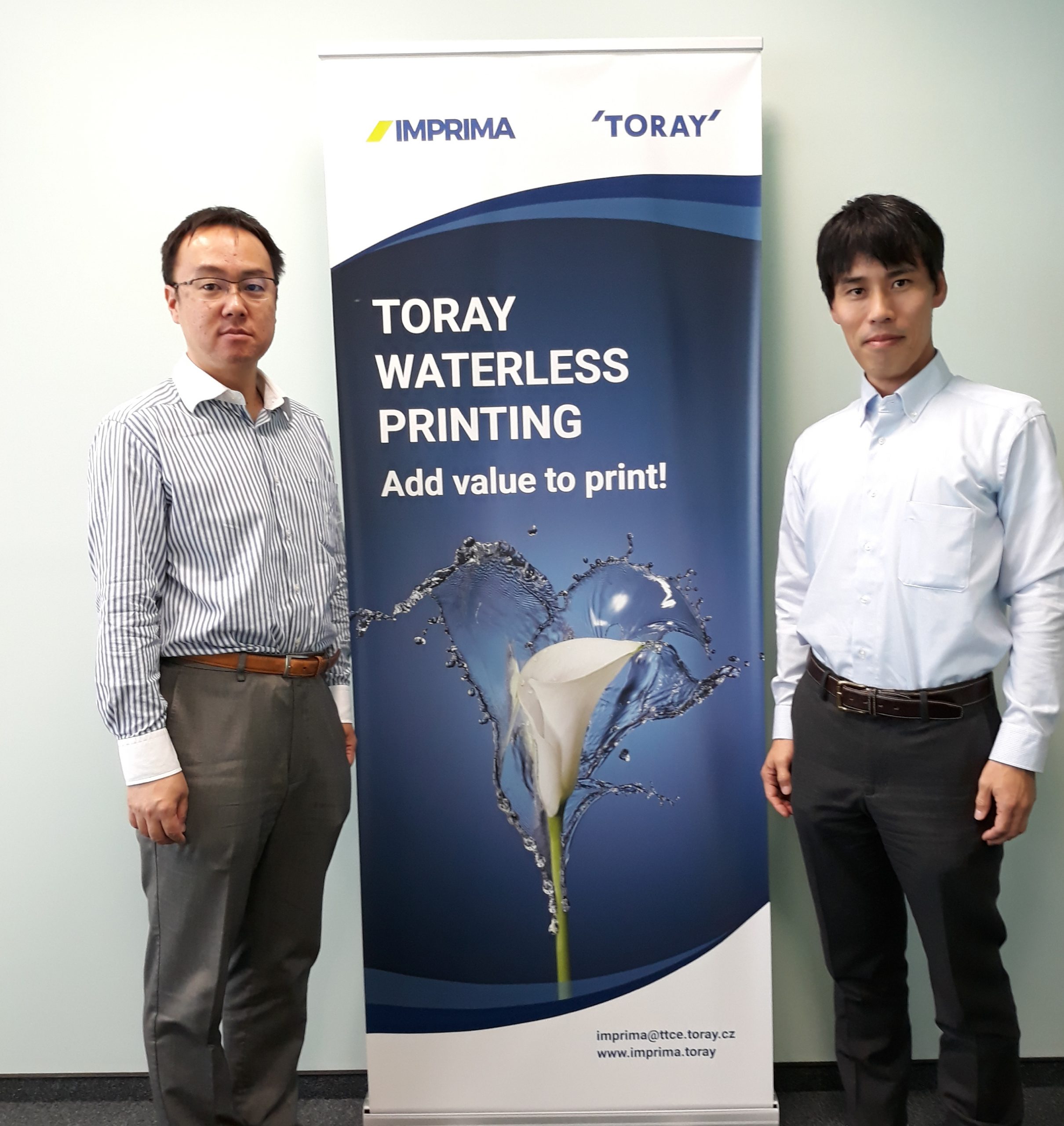 Mr. Mitsunori Hayashi and Mr. Kaoru Ueda posing before a Toray banner